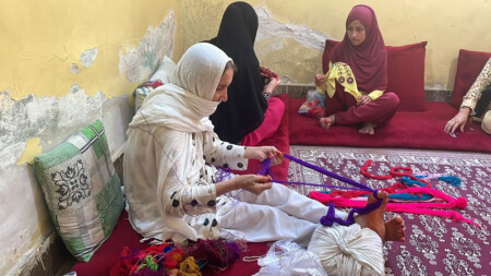 Women sitting in a room wokrung with emboroidery and sorting threads.