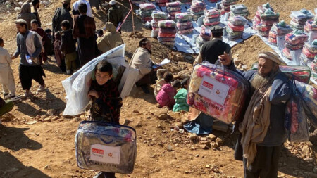 Several men and some children receive packages containing blankets, among other things.
