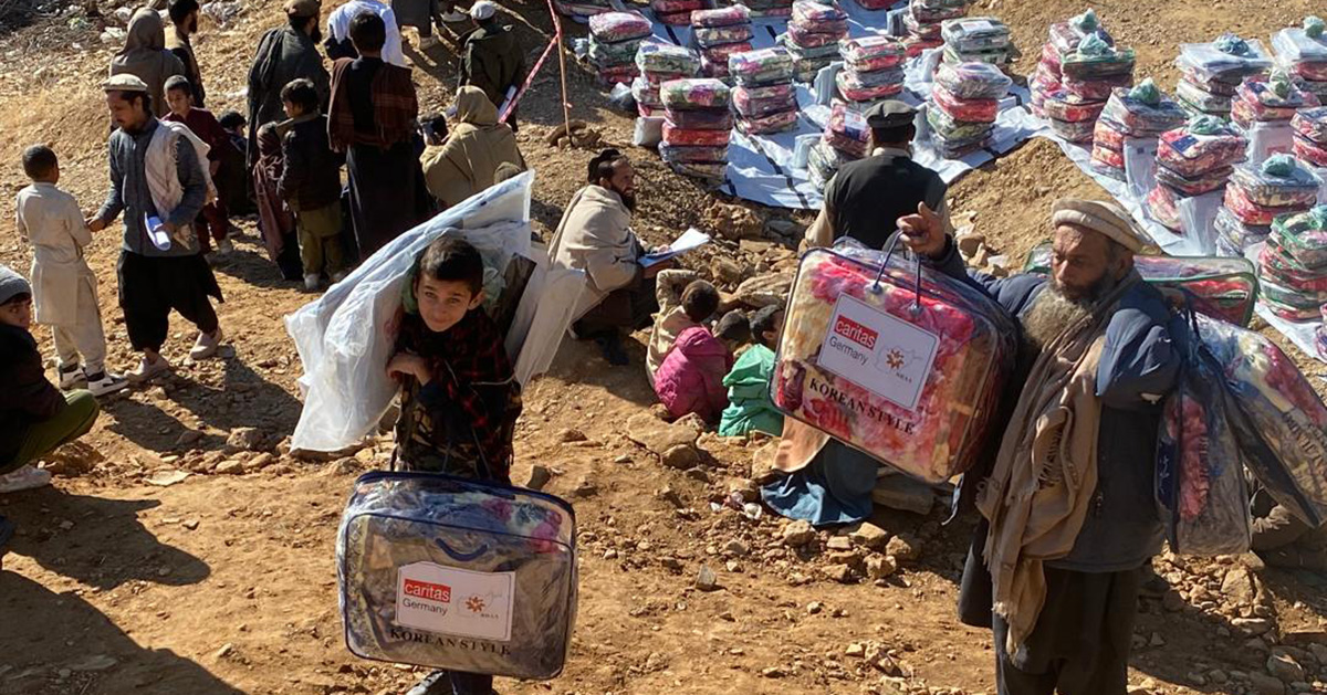 Several men and some children receive packages containing blankets, among other things.