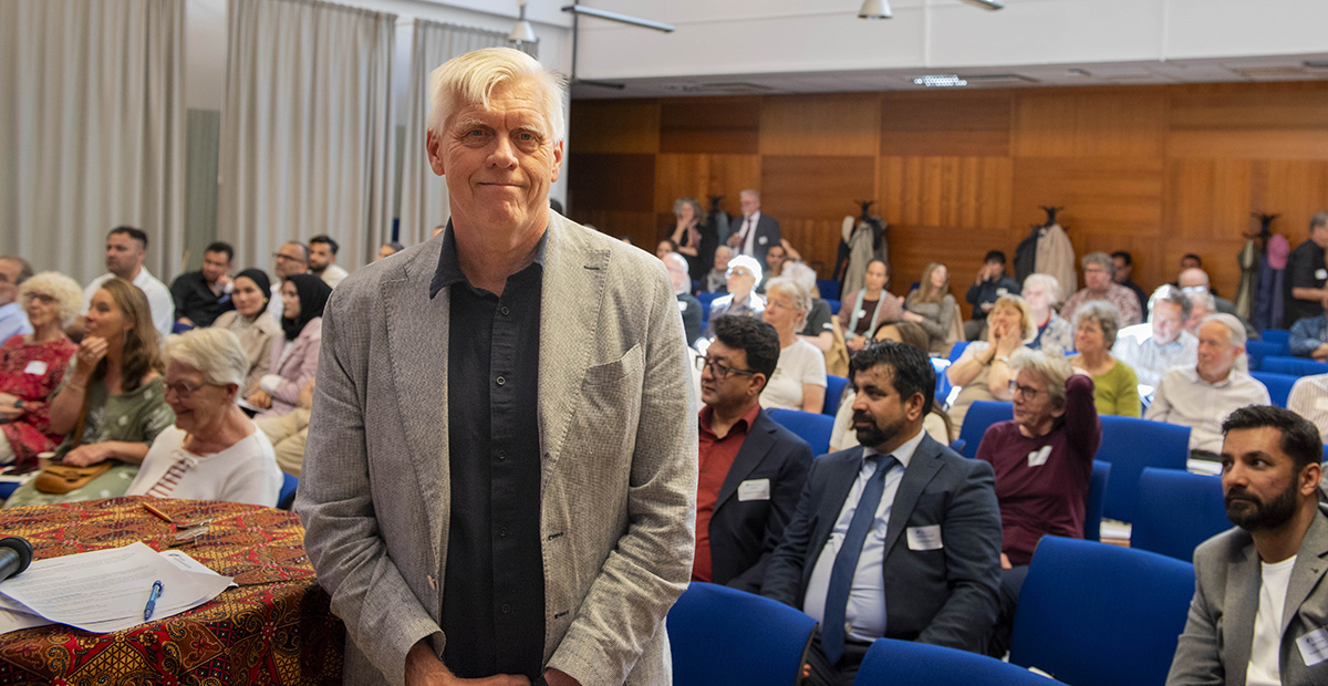 Man in front of a big meeting room full with people.