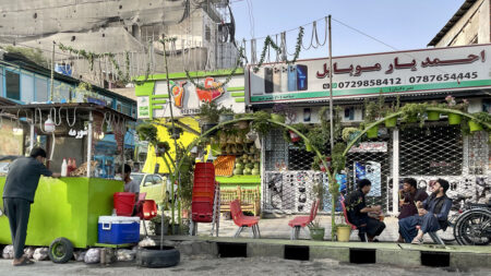 Street scene from Kabul with three young men talking to each other at a simple street cafe.